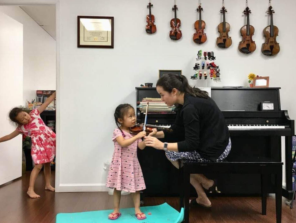 Dr. Nikki Ebisu teaching children violin